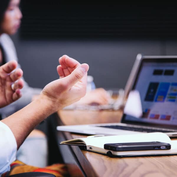 a closeup of someone gesturing with their hands sitting at a conference table