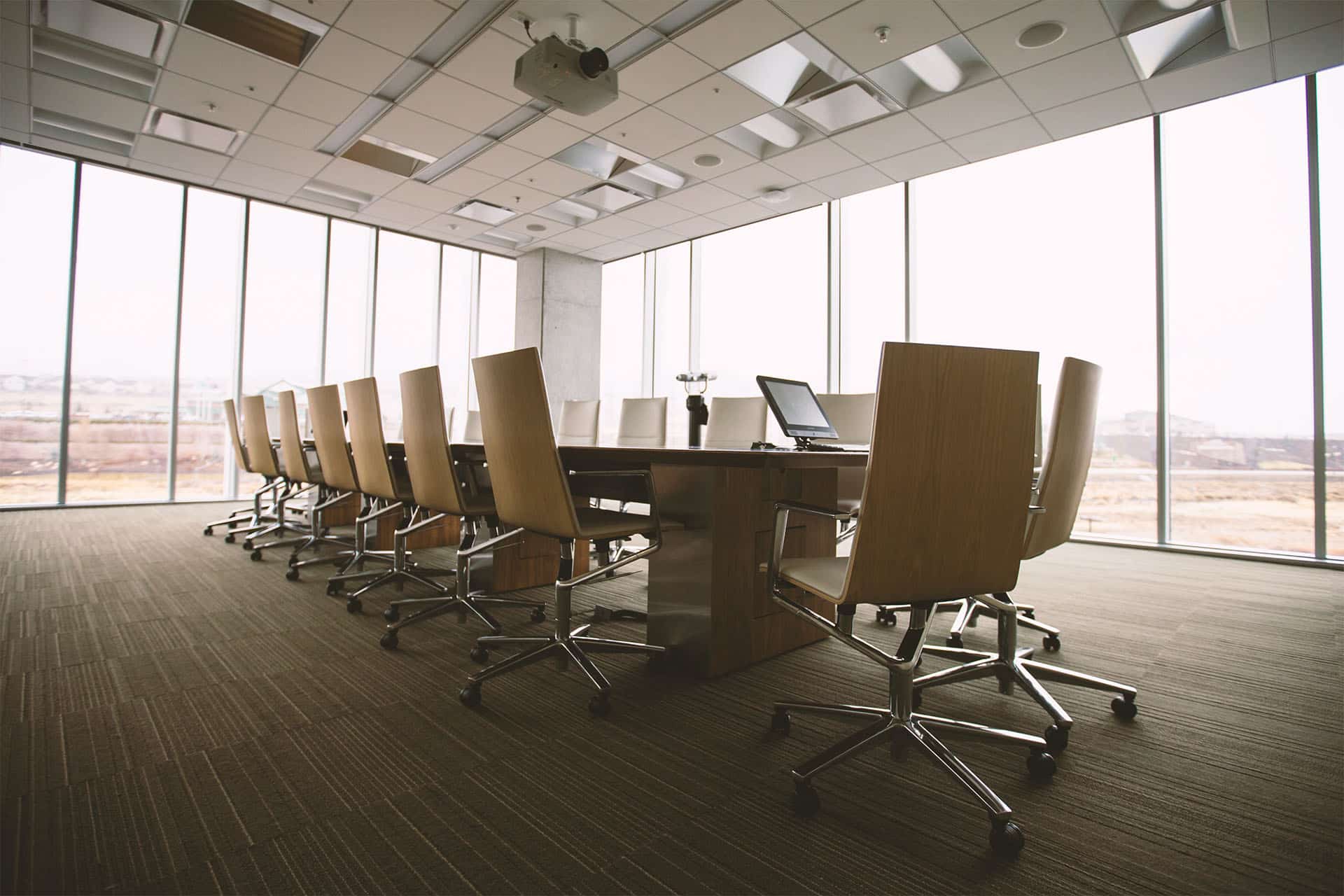 A conference room with a table and chairs in the middle surrounded by full length windows