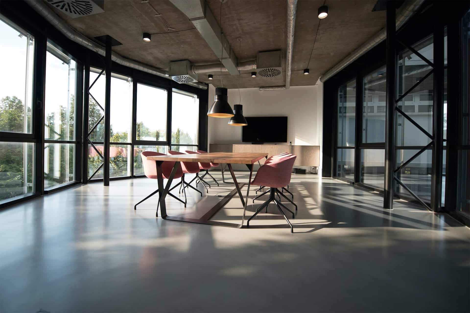 A conference room with a table and chairs in the middle surrounded by full length windows