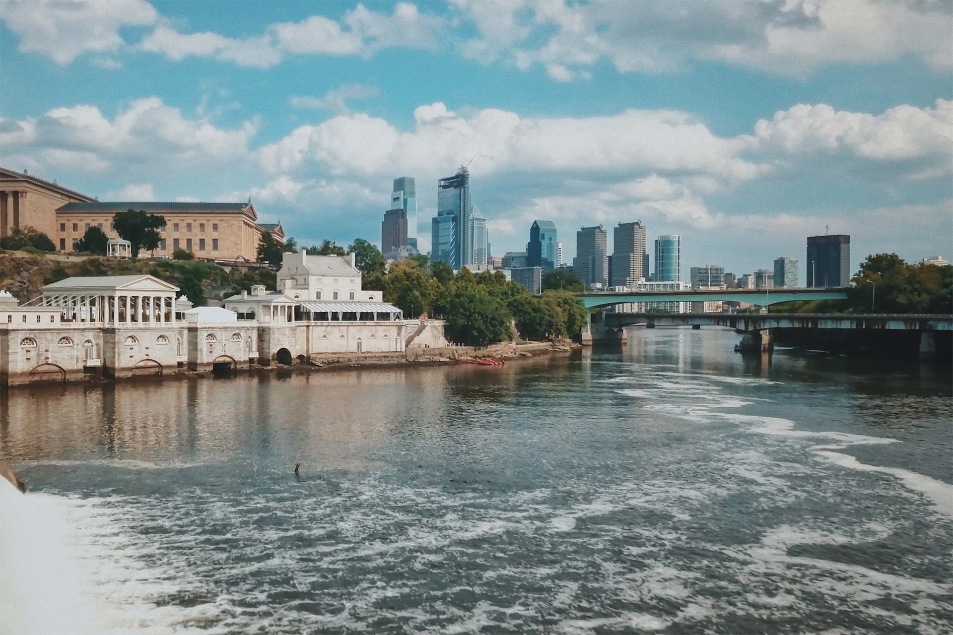 a river with buildings on the edge and a city skyline in the bancjground